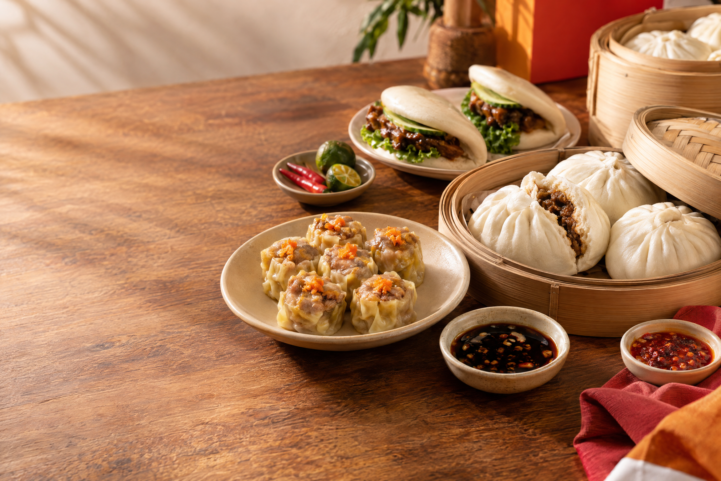 Steamed siopao, siomai, and cuapao arranged on plates and bamboo steamers